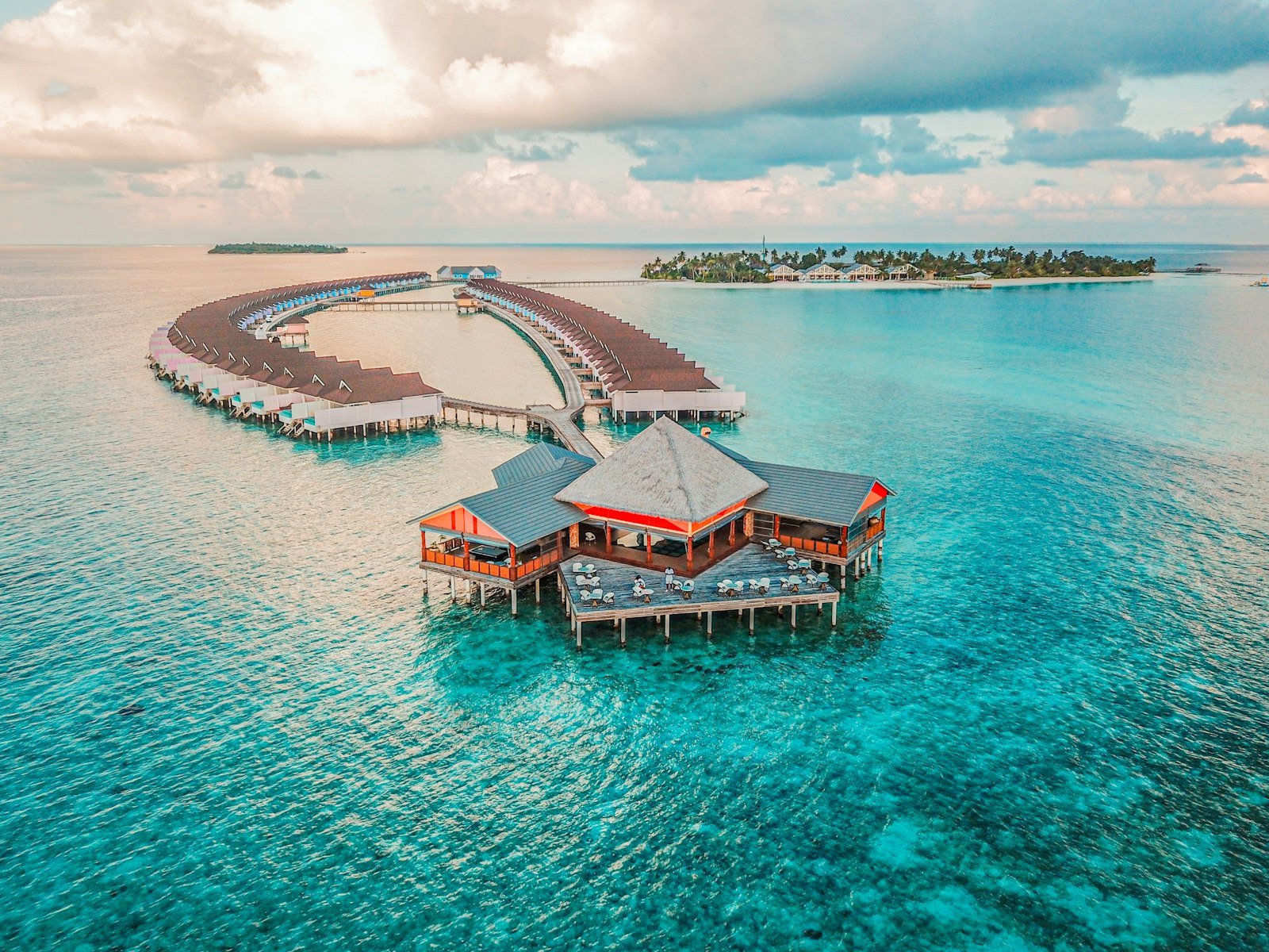 Aerial view of an island resort and overwater villas surrounded by turquoise water in the Maldives