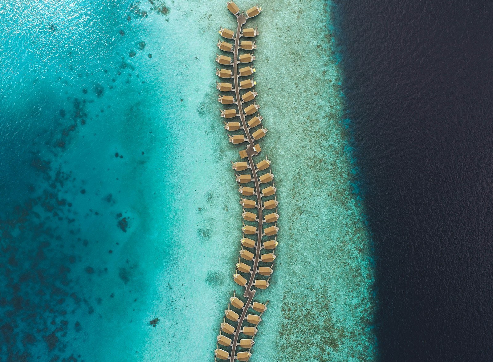 Water villas extending across a turquoise Maldivian reef and deep blue ocean